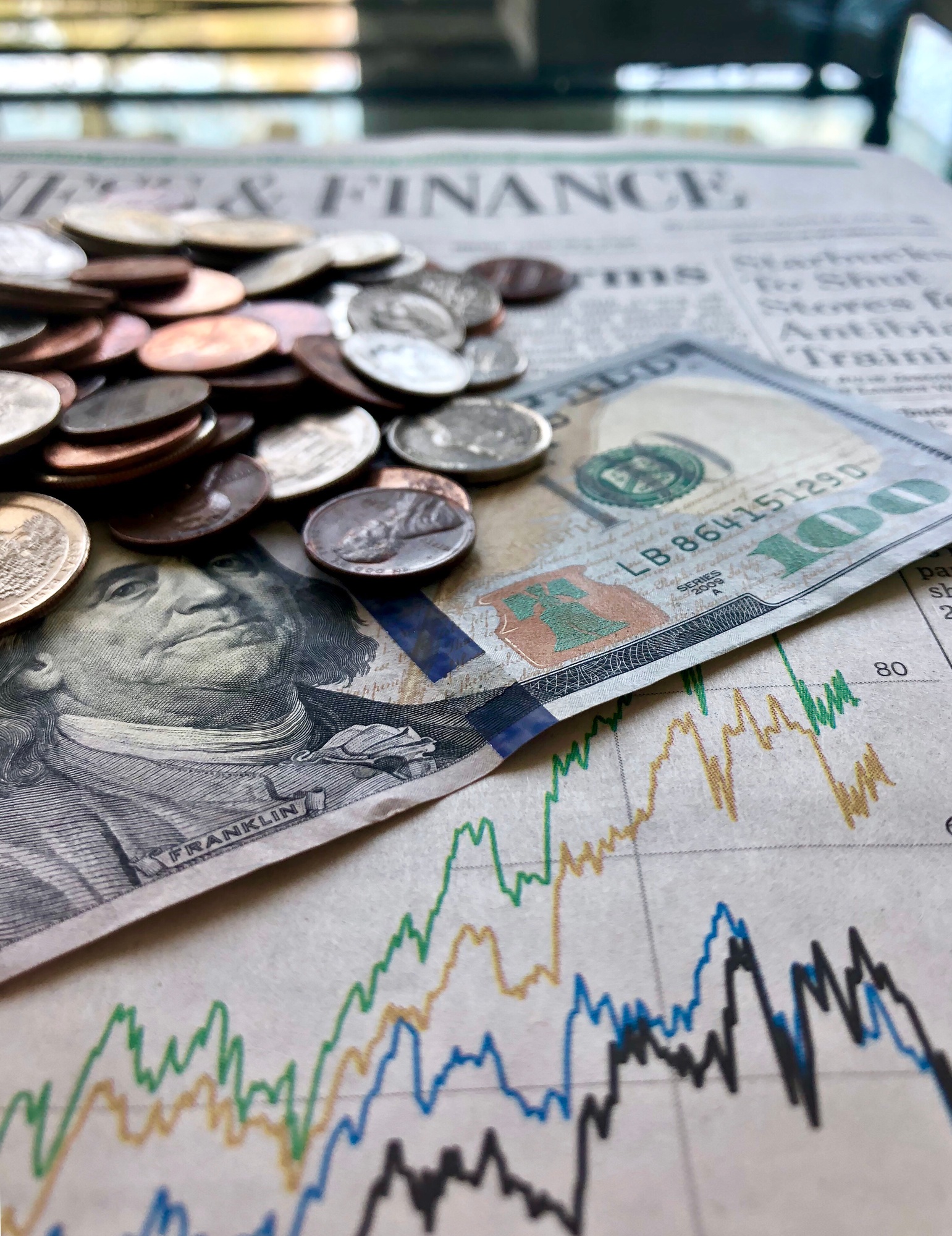 Money & Finances. Hundred dollar bill with coins on the news paper’s finances & stocks section.